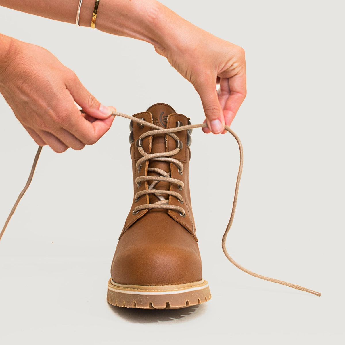 Hands adjusting the laces on a copper Rocky waterproof ankle boot