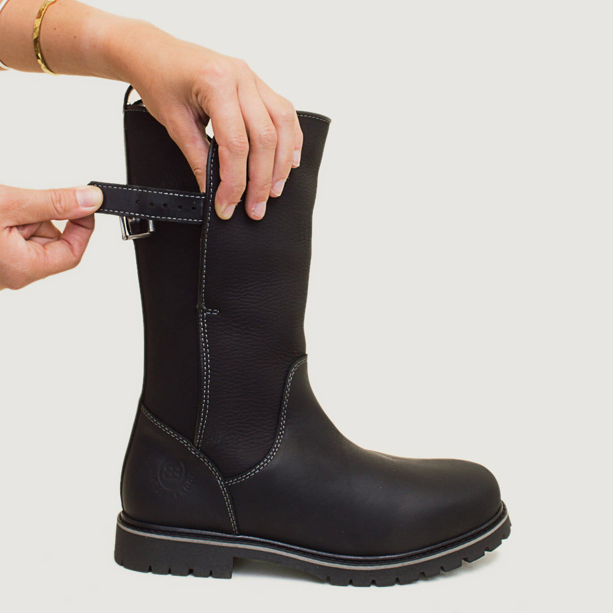 Bareback Quebec waterproof zip-up mid-calf boots in black leather, close-up of a hand adjusting the buckle strap