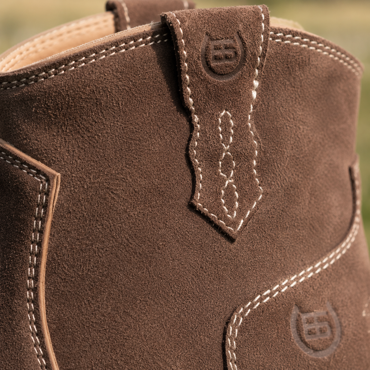 Close-up of a brown leather boot with stitching details and a brand logo.