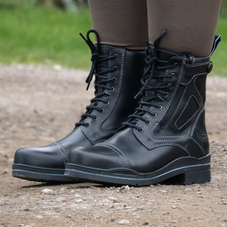 Black boots worn with brown leggings on a natural outdoor background