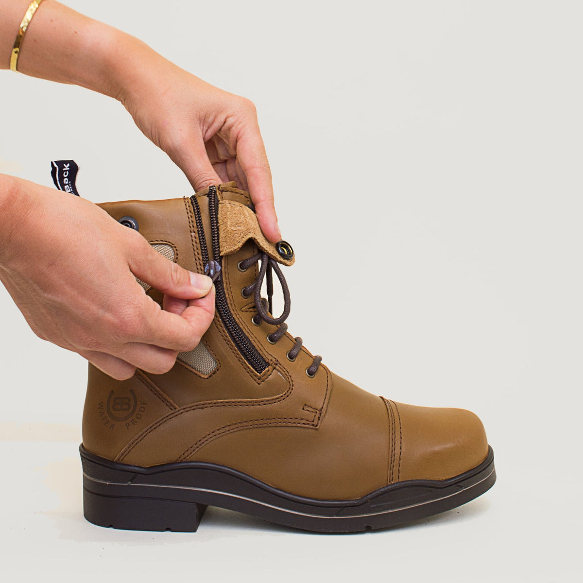 Bareback Kentucky Storm waterproof jodhpur boots in mocha, close-up of hands fastening the side zip