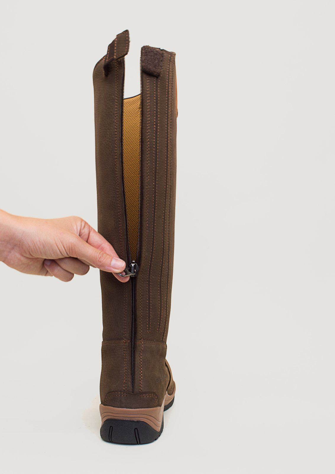 Hand opening the full-length rear zip on a Montana brown riding boot
