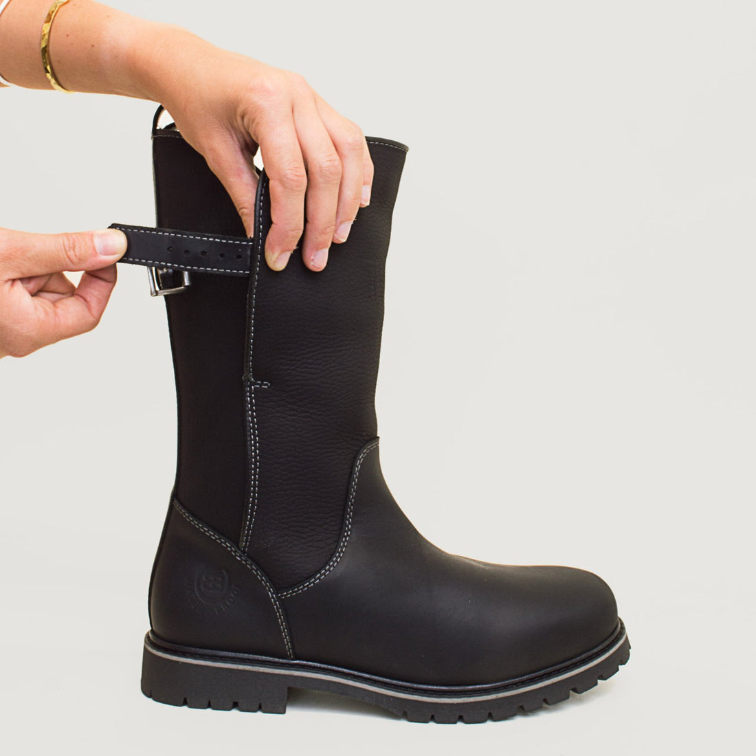 Bareback Quebec waterproof mid calf boots in black, close-up of hands releasing the back buckle strap
