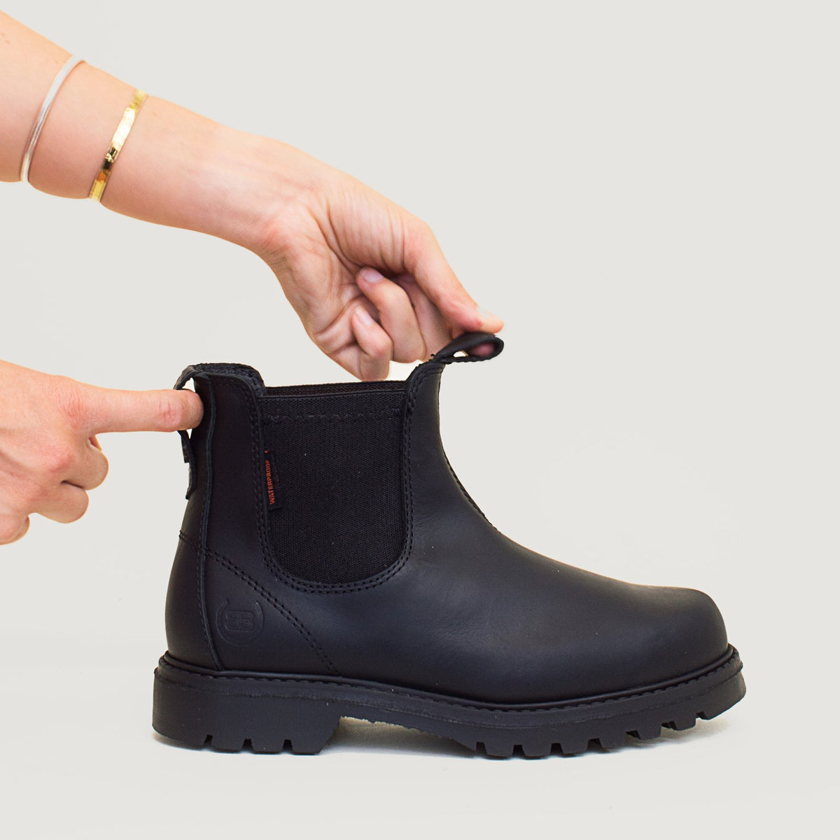 Bareback Vancouver Storm waterproof boots in black, close-up of hands pulling the side pull tabs